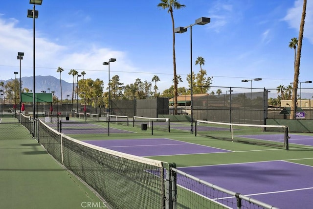 view of tennis court with community basketball court, fence, and a mountain view