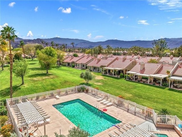 community pool featuring a mountain view, a fenced backyard, and a patio area