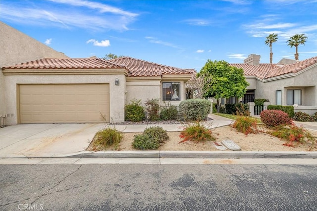 view of front of house with a tile roof, concrete driveway, stucco siding, and an attached garage