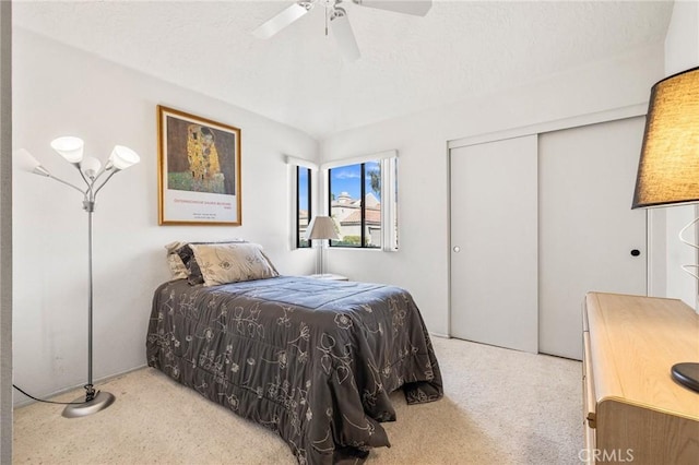 carpeted bedroom with a closet, a textured ceiling, and a ceiling fan