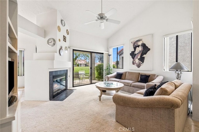 living room featuring a tiled fireplace, high vaulted ceiling, ceiling fan, and carpet flooring