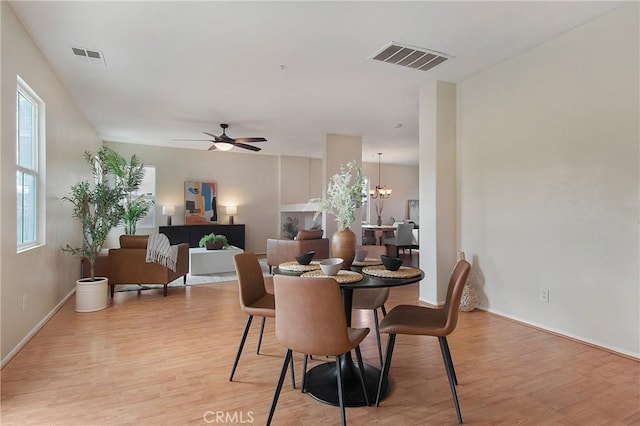 dining area featuring visible vents, light wood-style flooring, baseboards, and ceiling fan with notable chandelier