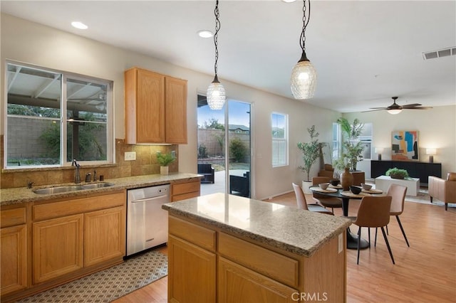kitchen featuring light wood-style flooring, tasteful backsplash, visible vents, dishwasher, and a sink