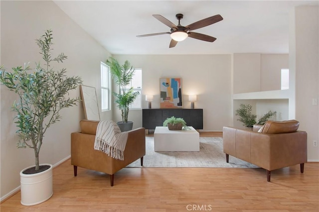 living area with ceiling fan, light wood finished floors, and baseboards