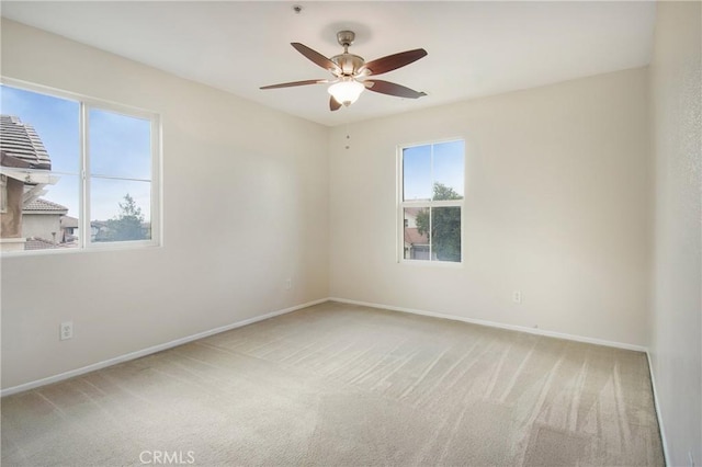 empty room with light carpet, baseboards, and a ceiling fan