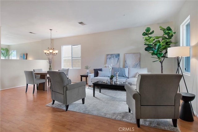 living area featuring visible vents, a notable chandelier, and wood finished floors