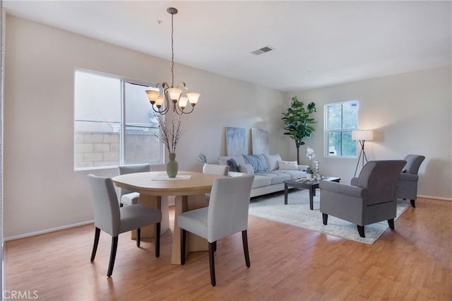 dining room with visible vents, light wood-style flooring, an inviting chandelier, and baseboards