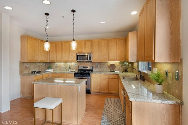 kitchen with light wood-style flooring, tasteful backsplash, a center island, a sink, and stainless steel appliances