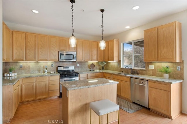 kitchen featuring tasteful backsplash, a center island, light wood-style floors, stainless steel appliances, and a sink