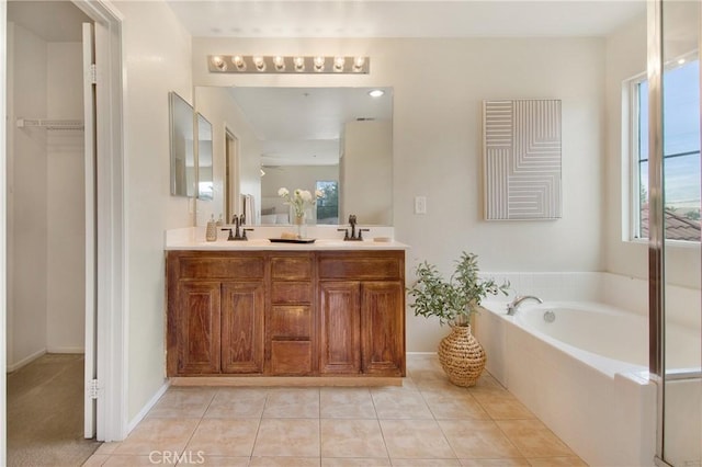 bathroom with tile patterned floors, a garden tub, double vanity, and a sink
