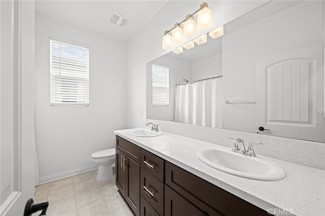 full bath featuring toilet, double vanity, a sink, and visible vents