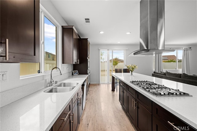 26382 Bramble Wood Cir, Menifee, CA 92584 - kitchen with appliances with stainless steel finishes, island range hood, dark brown cabinetry, light wood-style floors, and recessed lighting