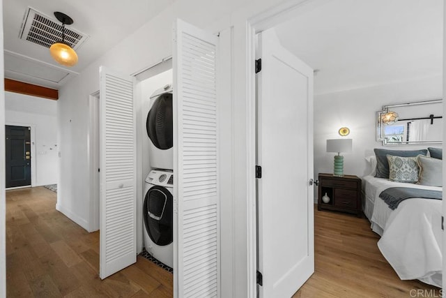 laundry area featuring visible vents, stacked washer and clothes dryer, laundry area, and light wood-style floors