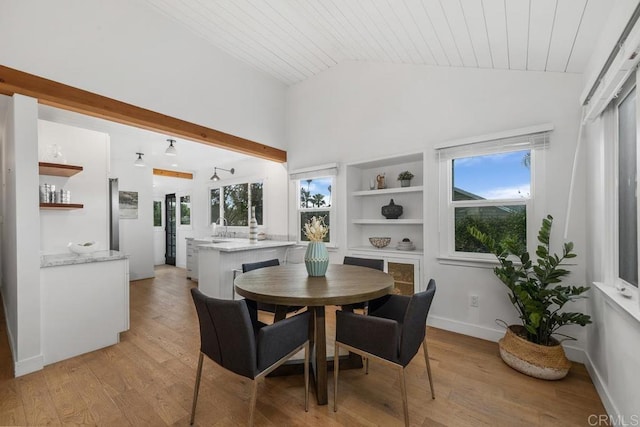dining space featuring vaulted ceiling, wooden ceiling, built in shelves, light wood finished floors, and baseboards