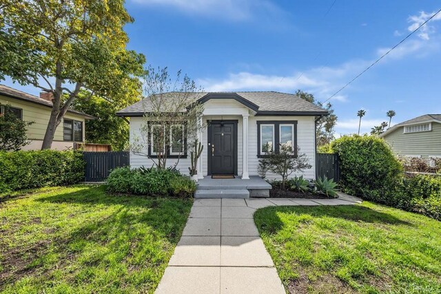 bungalow-style house with a front yard and fence