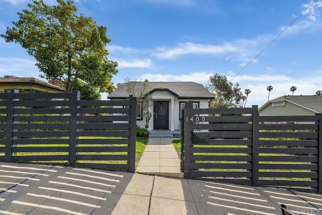 bungalow-style house with a shingled roof, a gate, and a fenced front yard