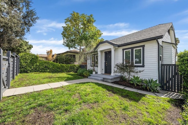 bungalow-style house with fence and a front lawn