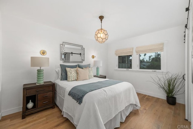 bedroom featuring baseboards, a barn door, and light wood-style floors