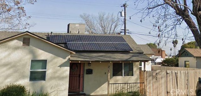 713 Charlana Dr, Bakersfield, CA 93308 - view of front of home featuring stucco siding, a shingled roof, fence, and solar panels