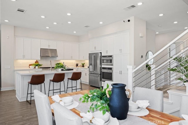 dining space with recessed lighting, stairway, visible vents, and wood finished floors