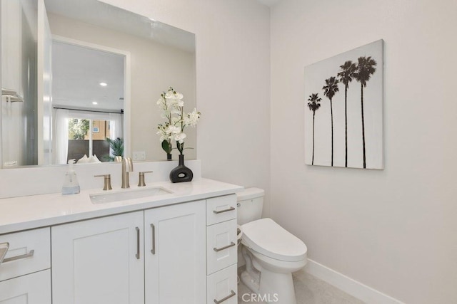 bathroom featuring toilet, vanity, and baseboards