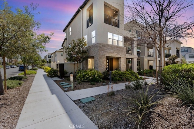 property exterior at dusk with stucco siding and stone siding