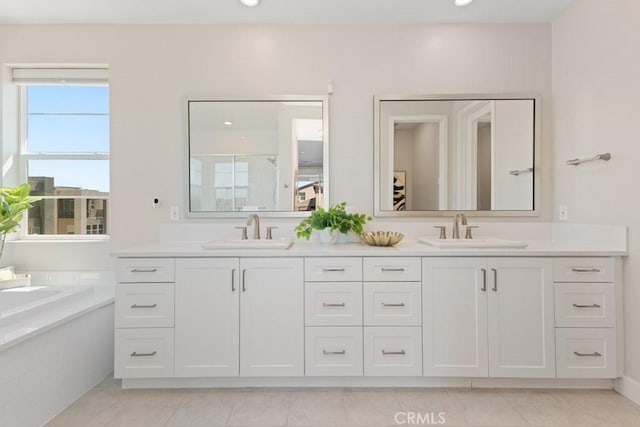 bathroom featuring recessed lighting, double vanity, a bath, and a sink