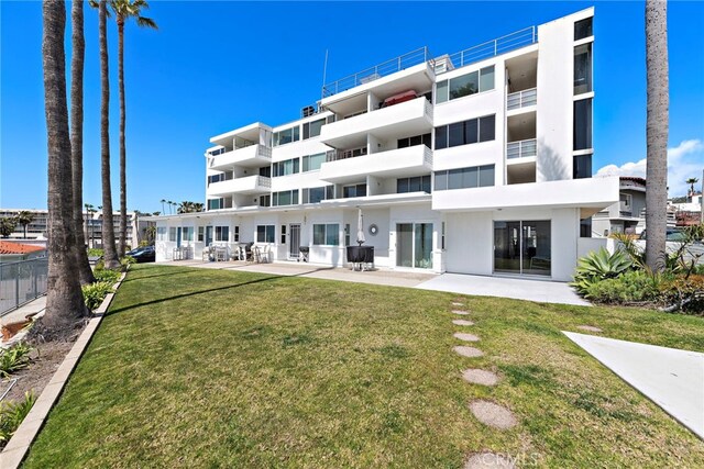 rear view of property featuring a lawn and a patio area
