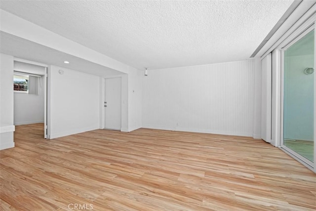 unfurnished living room featuring a textured ceiling, light wood-style flooring, and baseboards