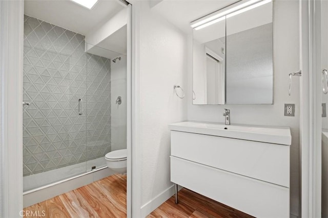 full bathroom featuring wood finished floors, a shower stall, toilet, and vanity