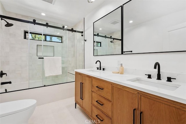 full bathroom with a sink, combined bath / shower with glass door, toilet, and double vanity