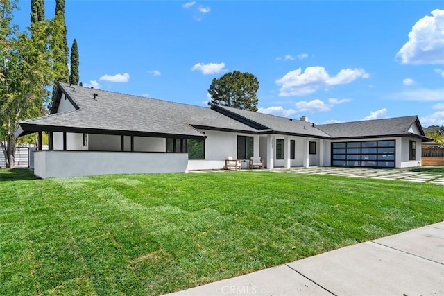 view of front facade with stucco siding, a shingled roof, a front lawn, and a garage