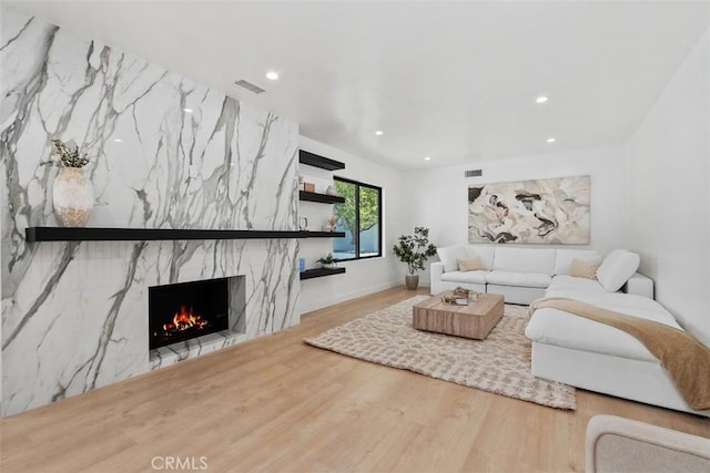 living room featuring a premium fireplace, visible vents, wood finished floors, and recessed lighting