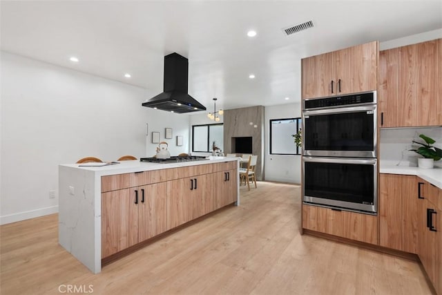 2037 Rayshire St, Thousand Oaks, CA 91362 - kitchen with exhaust hood, appliances with stainless steel finishes, a center island, light wood-style flooring, and light countertops