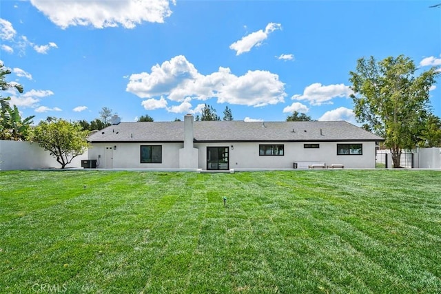 back of house featuring a yard, central AC, fence, and stucco siding