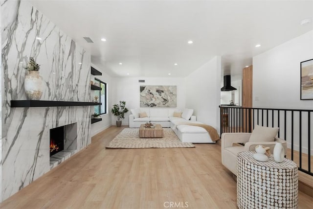 living area featuring visible vents, a high end fireplace, wood finished floors, and recessed lighting