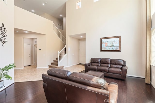 living area featuring recessed lighting, stairway, a high ceiling, wood-type flooring, and baseboards