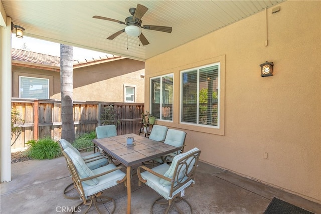 view of patio with outdoor dining area, fence, and ceiling fan