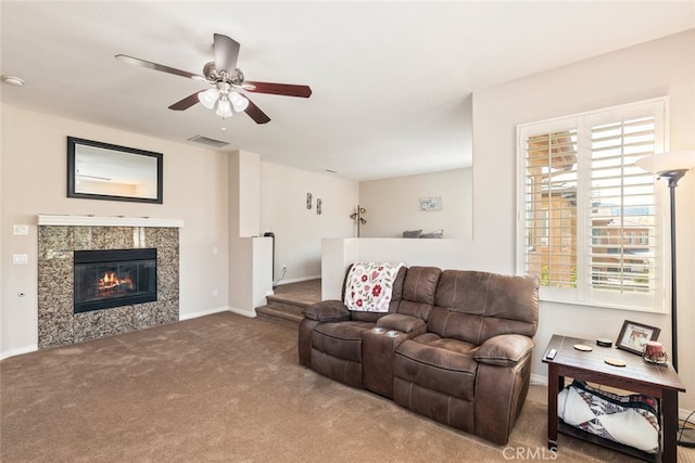 carpeted living room with a fireplace, visible vents, baseboards, and ceiling fan