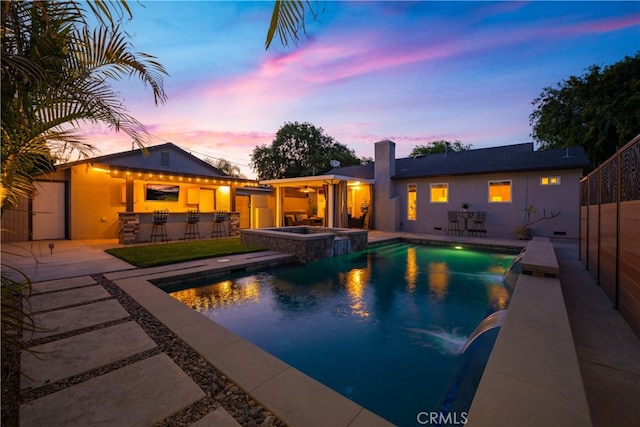 view of swimming pool featuring outdoor dry bar, a pool with connected hot tub, and a patio