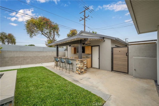 exterior space with outdoor dry bar, a ceiling fan, a patio, and a fenced backyard