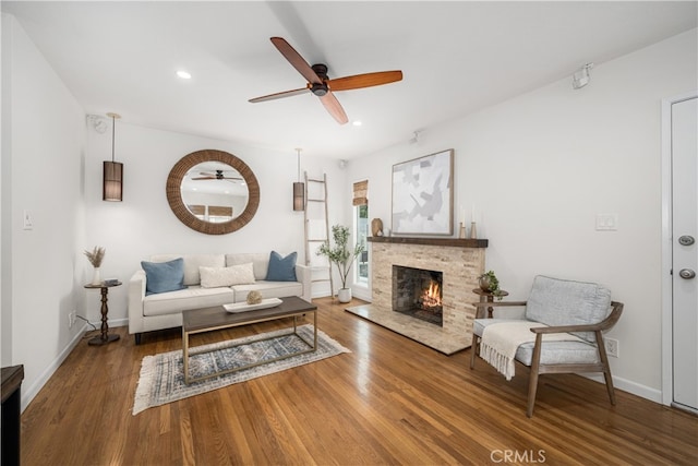 living area featuring a ceiling fan, wood finished floors, a lit fireplace, baseboards, and recessed lighting