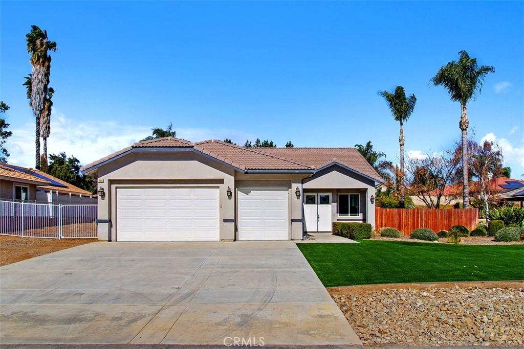 14084 Moonridge Dr, Riverside, CA 92503 - ranch-style house featuring a front yard, fence, concrete driveway, an attached garage, and stucco siding