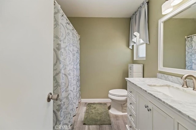 bathroom featuring vanity, baseboards, wood finished floors, and toilet