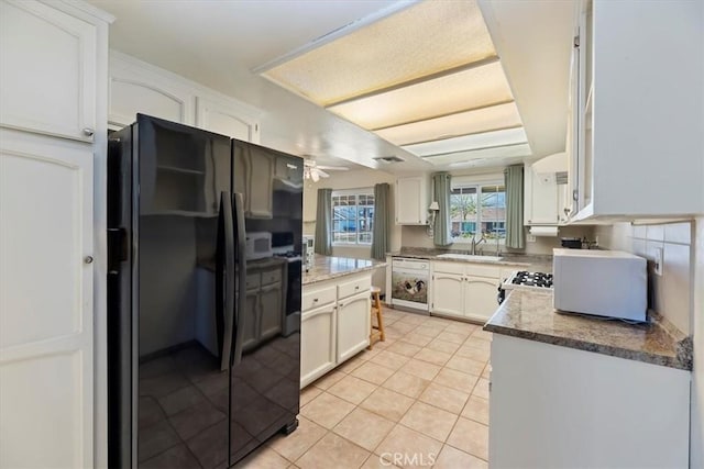 kitchen featuring ceiling fan, white cabinets, freestanding refrigerator, and light tile patterned flooring