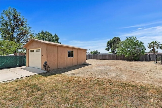 detached garage featuring fence and concrete driveway