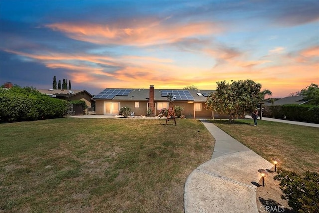 view of front facade with roof mounted solar panels, fence, and a front yard