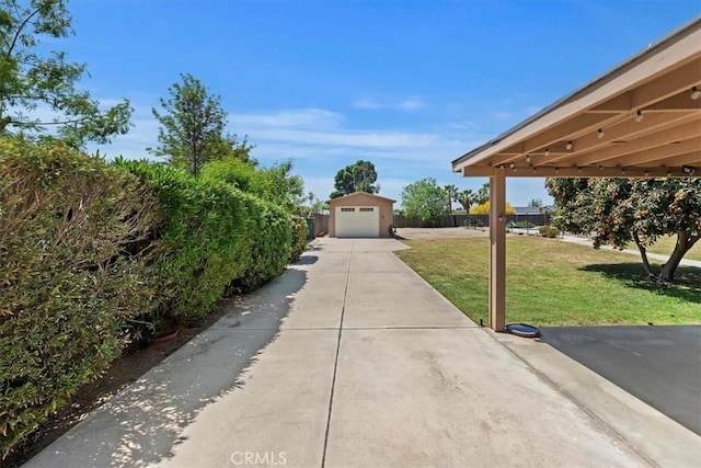 exterior space featuring a detached garage, fence, driveway, and an outbuilding