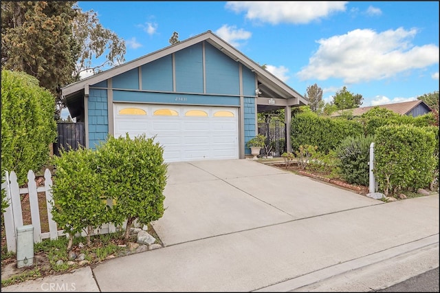 view of front facade featuring an attached garage, driveway, and fence