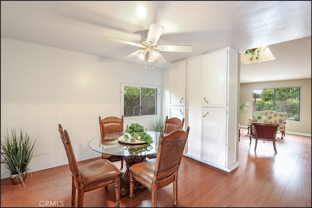 dining space featuring wainscoting, wood finished floors, and ceiling fan